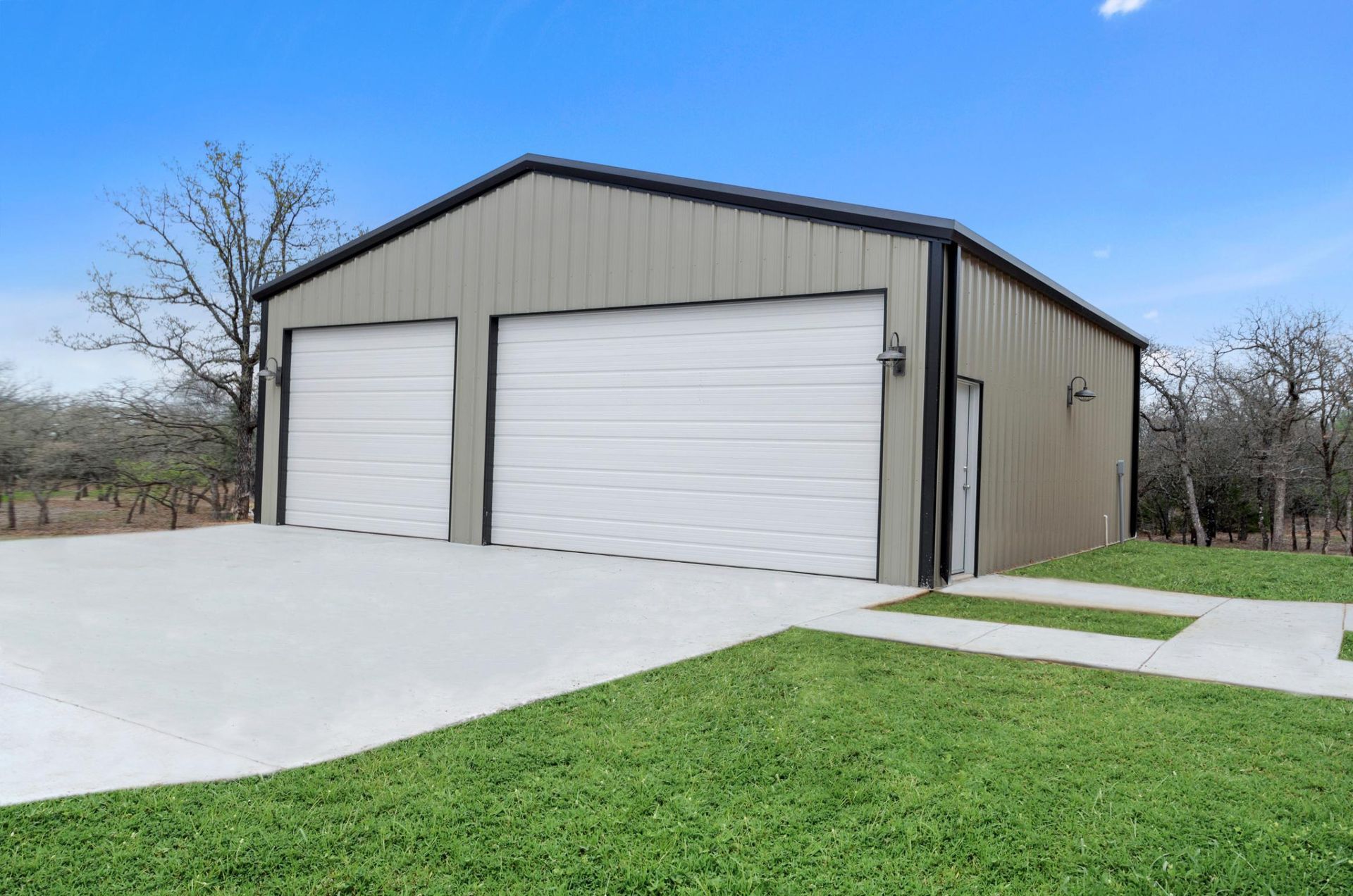 A metal garage with two white garage doors and a concrete driveway.