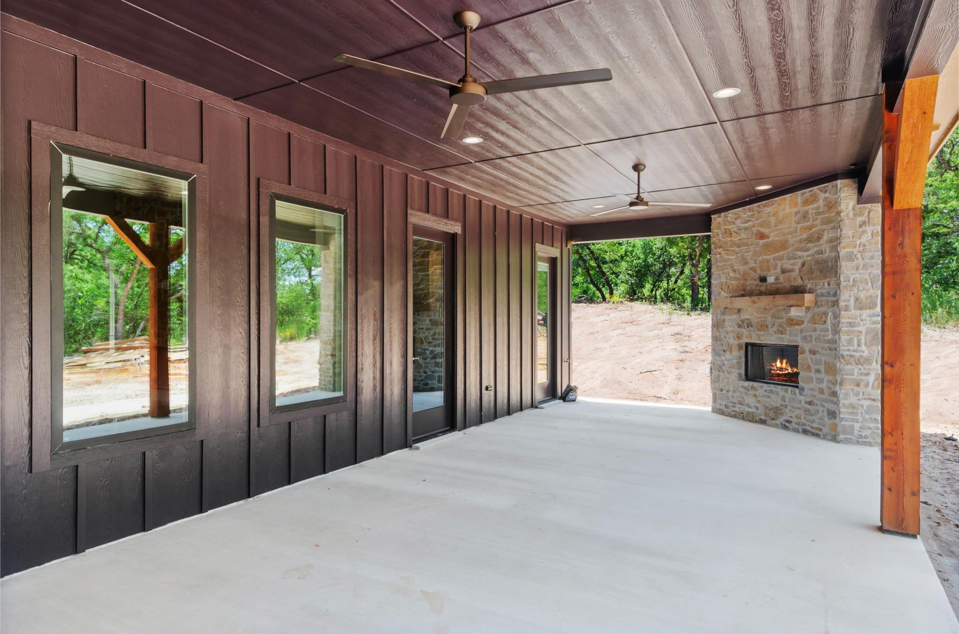 A large covered patio with a fireplace and a ceiling fan.