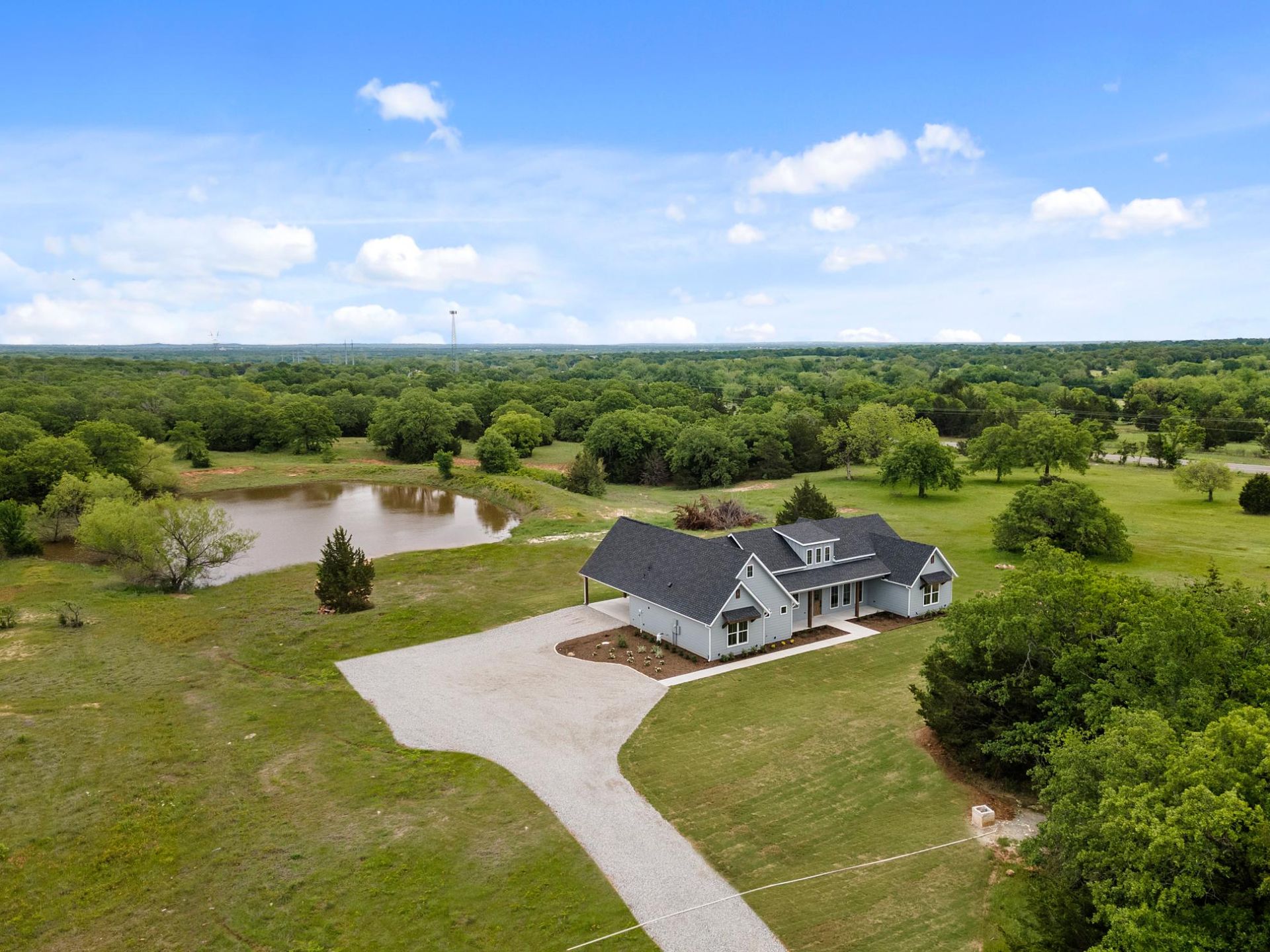 An aerial view of a house in the middle of a grassy field.