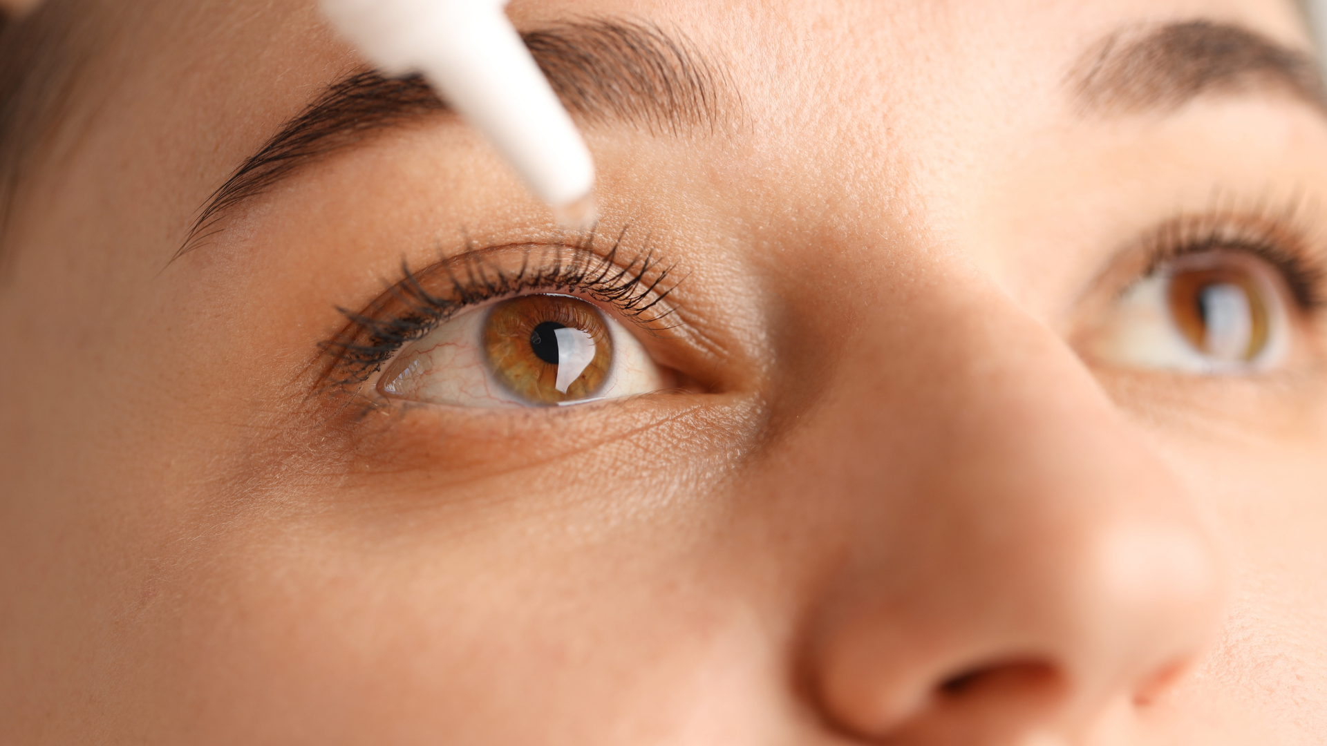 Close-up of a person’s eyes with a makeup brush applying eyeliner or mascara