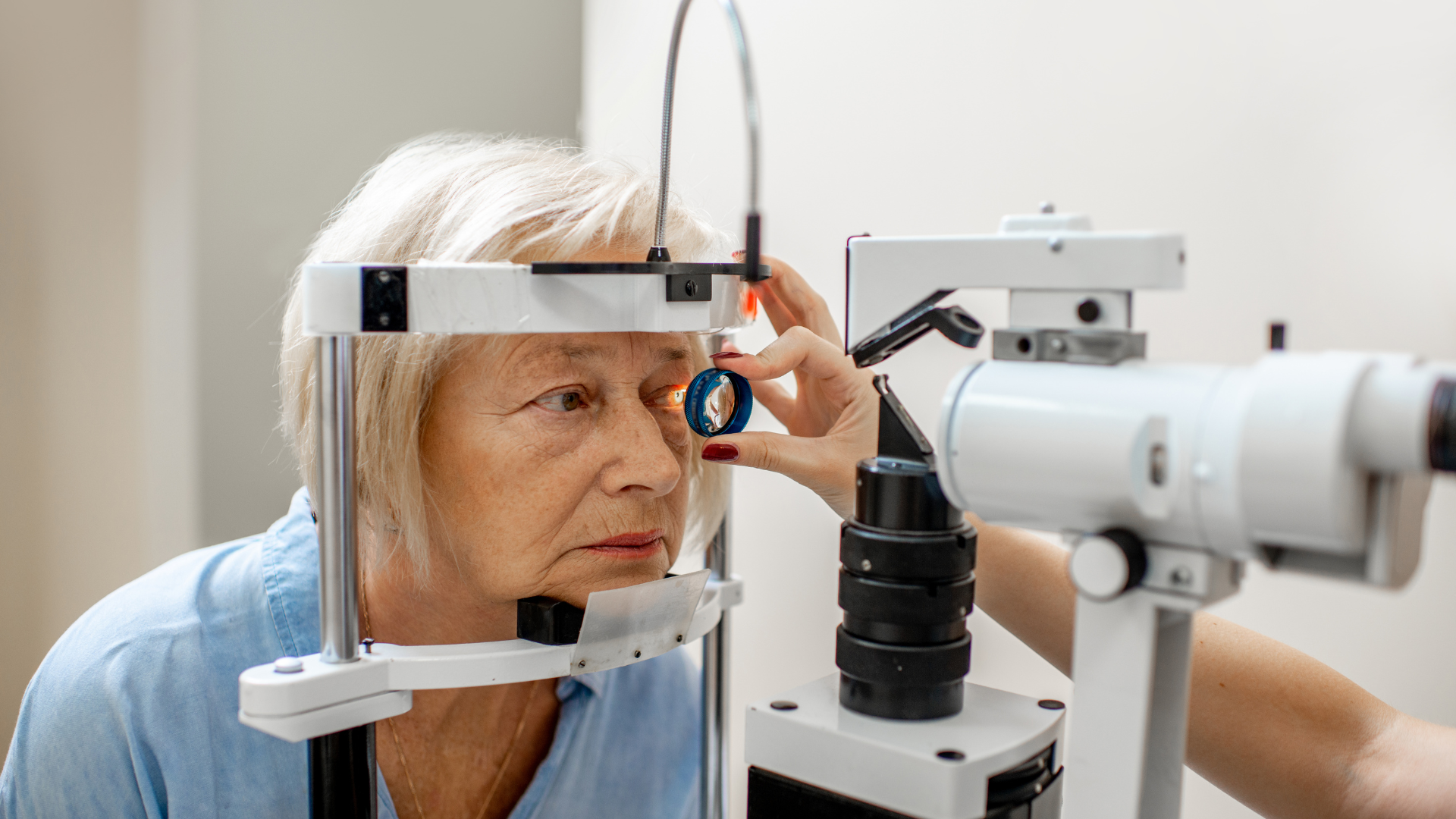 Patient undergoing eye exam with ophthalmic equipment and doctor adjusting the lens