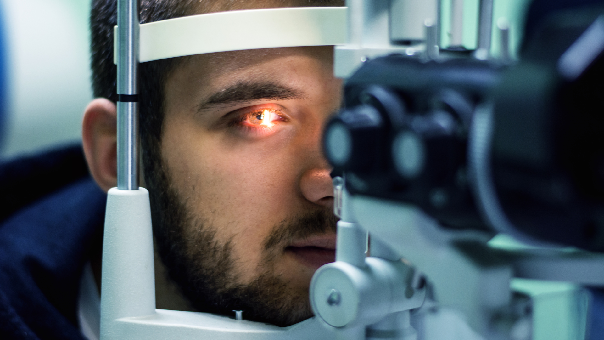 Person undergoing an eye exam with a glowing red eye viewed through medical equipment