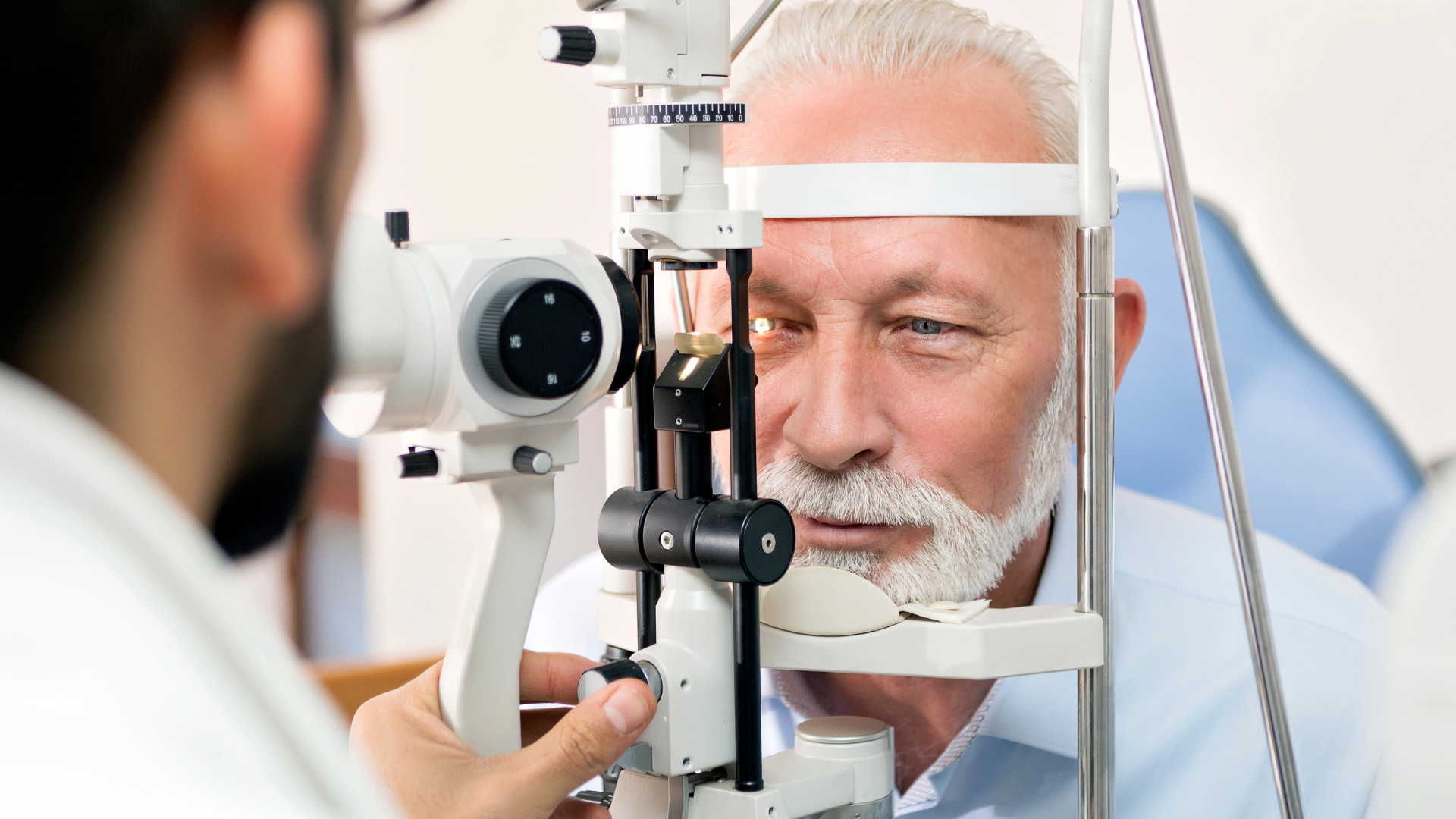 Optometrist examining a patient’s eye with a slit lamp in a bright clinic