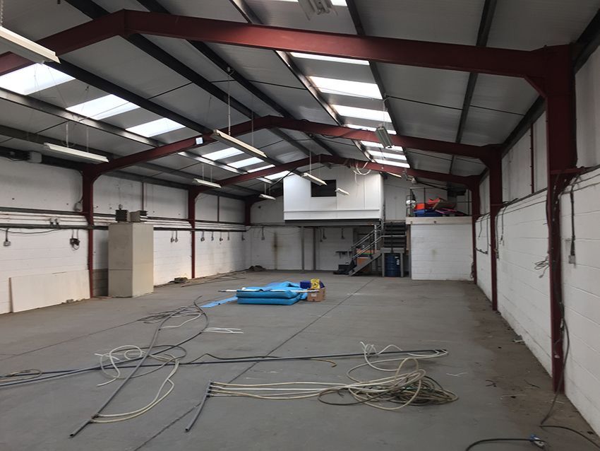 A large empty warehouse with a blue tarp on the floor