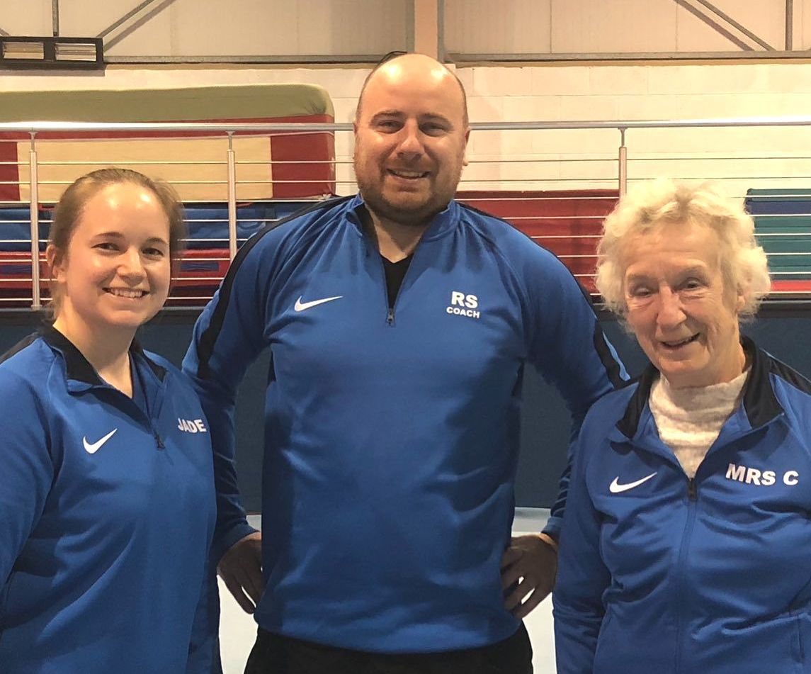 A man and two women are posing for a picture in a gym.