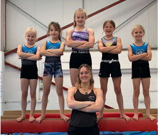 A group of young girls are posing for a picture with their arms crossed