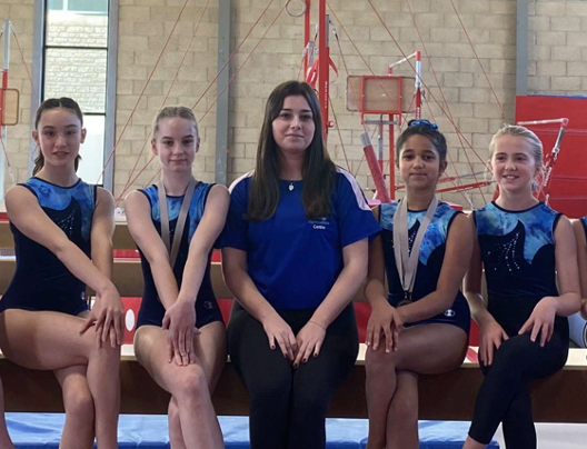 A group of gymnasts are posing for a picture with their coach