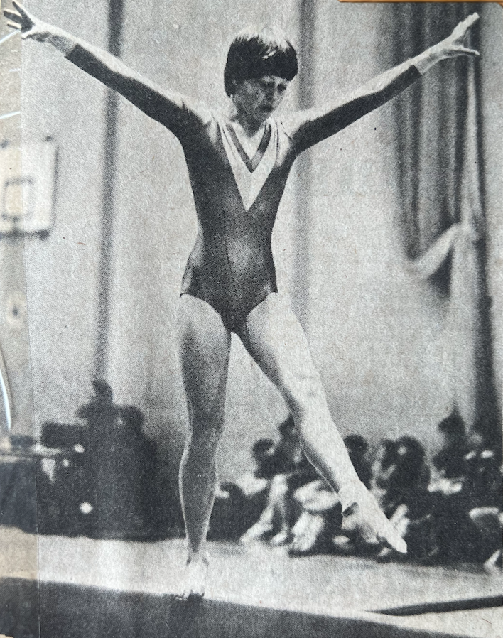 A black and white photo of a gymnast on a balance beam