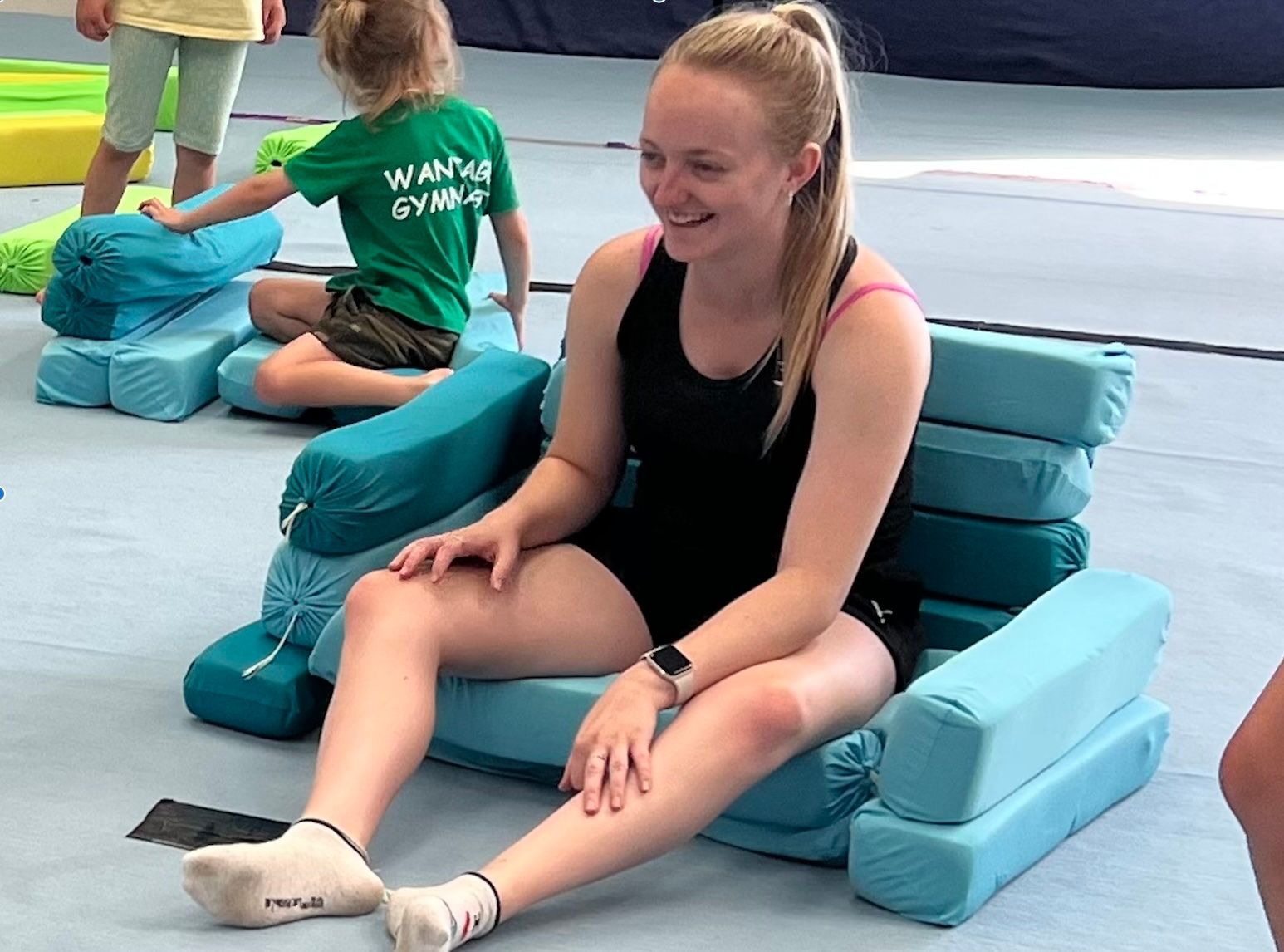 A woman is sitting on a chair with her legs uncrossed.