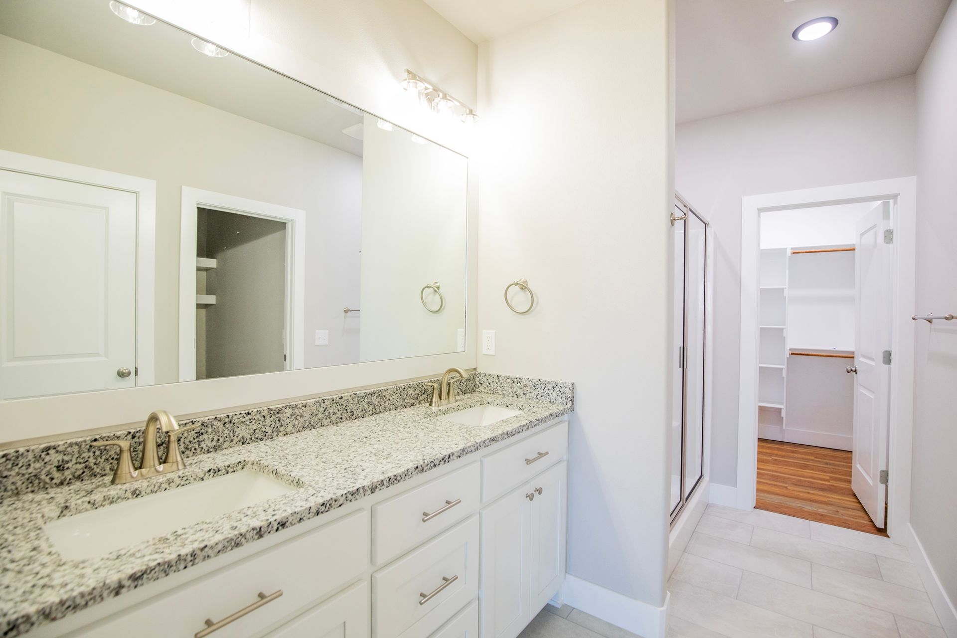Bathroom with double vanity, large mirror, and walk-in closet in a home.
