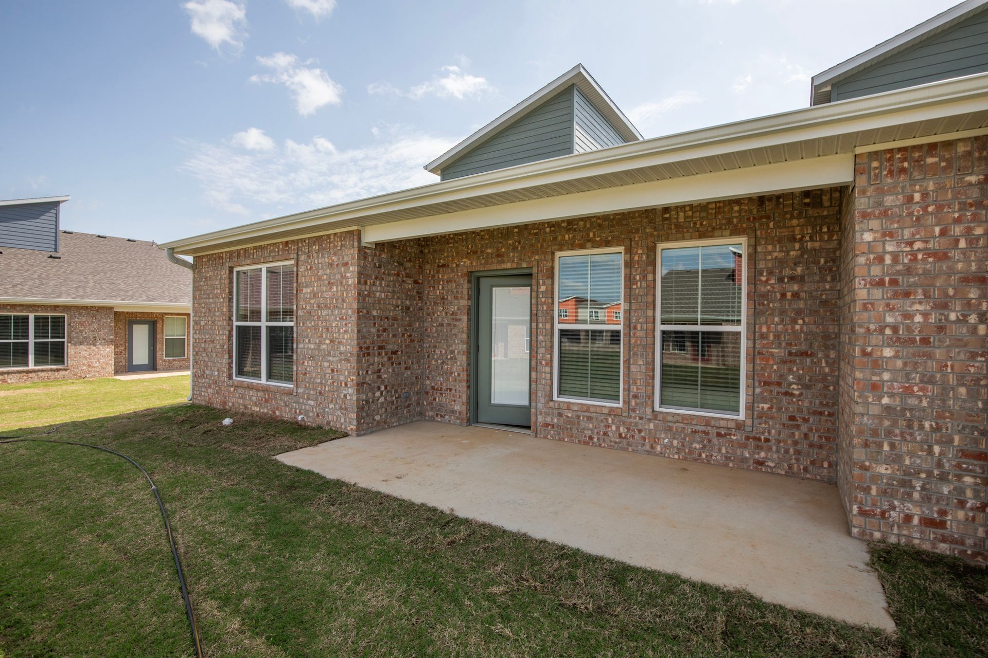 Bright white kitchen with island and wood floors, open to a living area with windows.