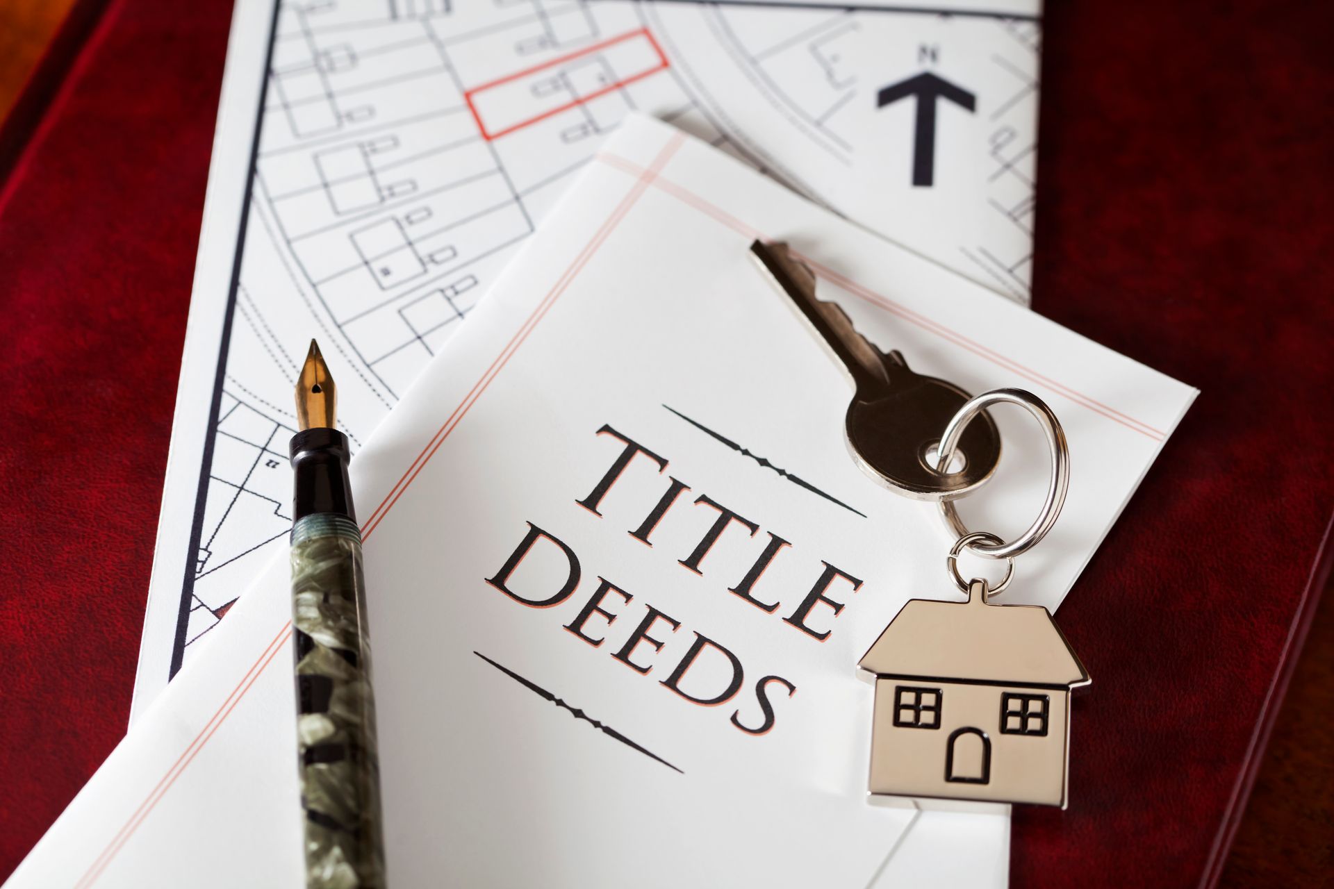 Title deeds with house key, pen, and map of property.