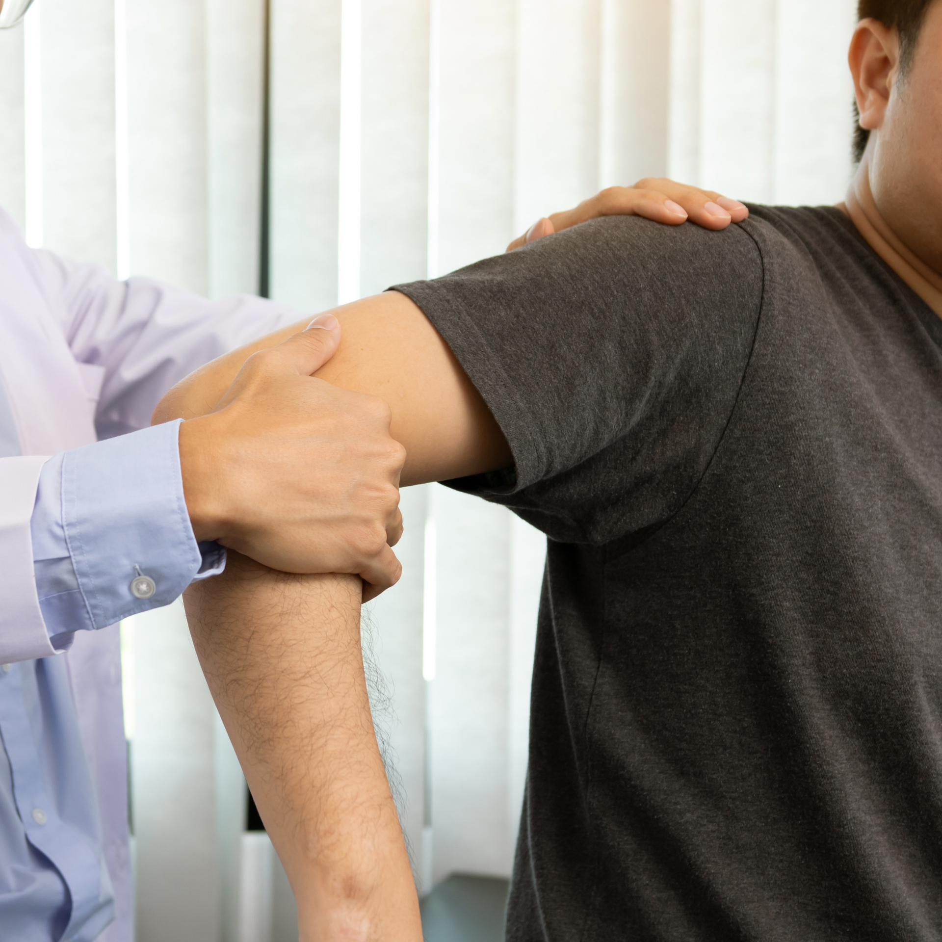 A young woman is sitting on a bed while a doctor examines her leg.