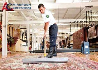 A man is cleaning a rug in a carpet cleaning shop.