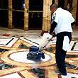 A man is polishing a marble floor with a machine.