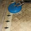 A blue vacuum cleaner is cleaning a tile floor.