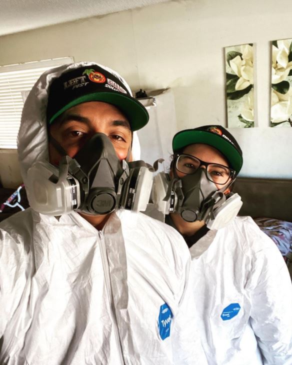 A man and a woman are wearing protective suits and masks.