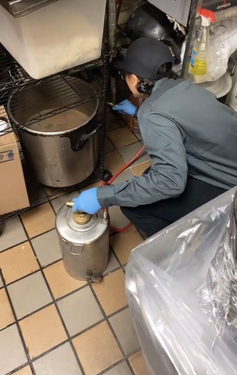 A man is kneeling down in a kitchen next to a pot.