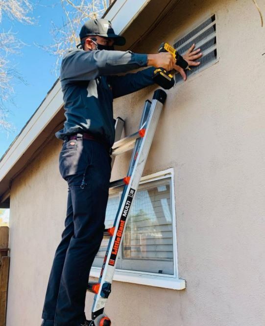 A man is standing on a ladder fixing a window