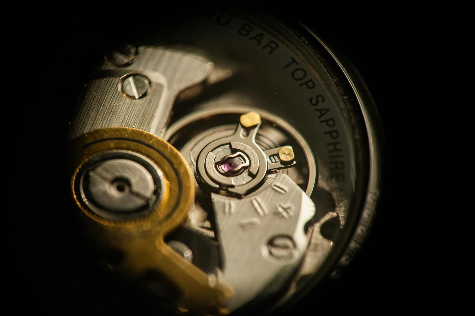 Hand holding a phone beside a teacup on a table, wearing a gold wristwatch in a café.
