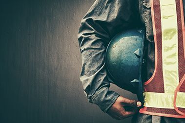 Construction worker with reflective vest holding helmet under arm