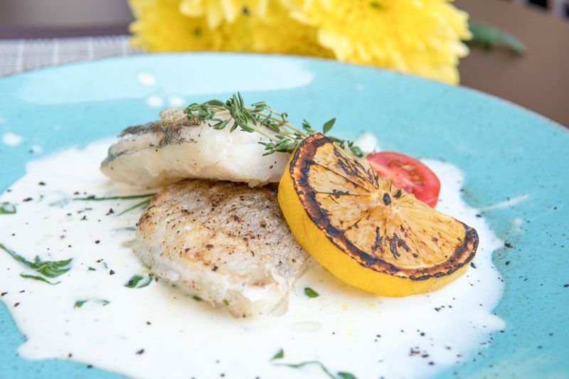 A blue plate topped with fish and a slice of lemon.