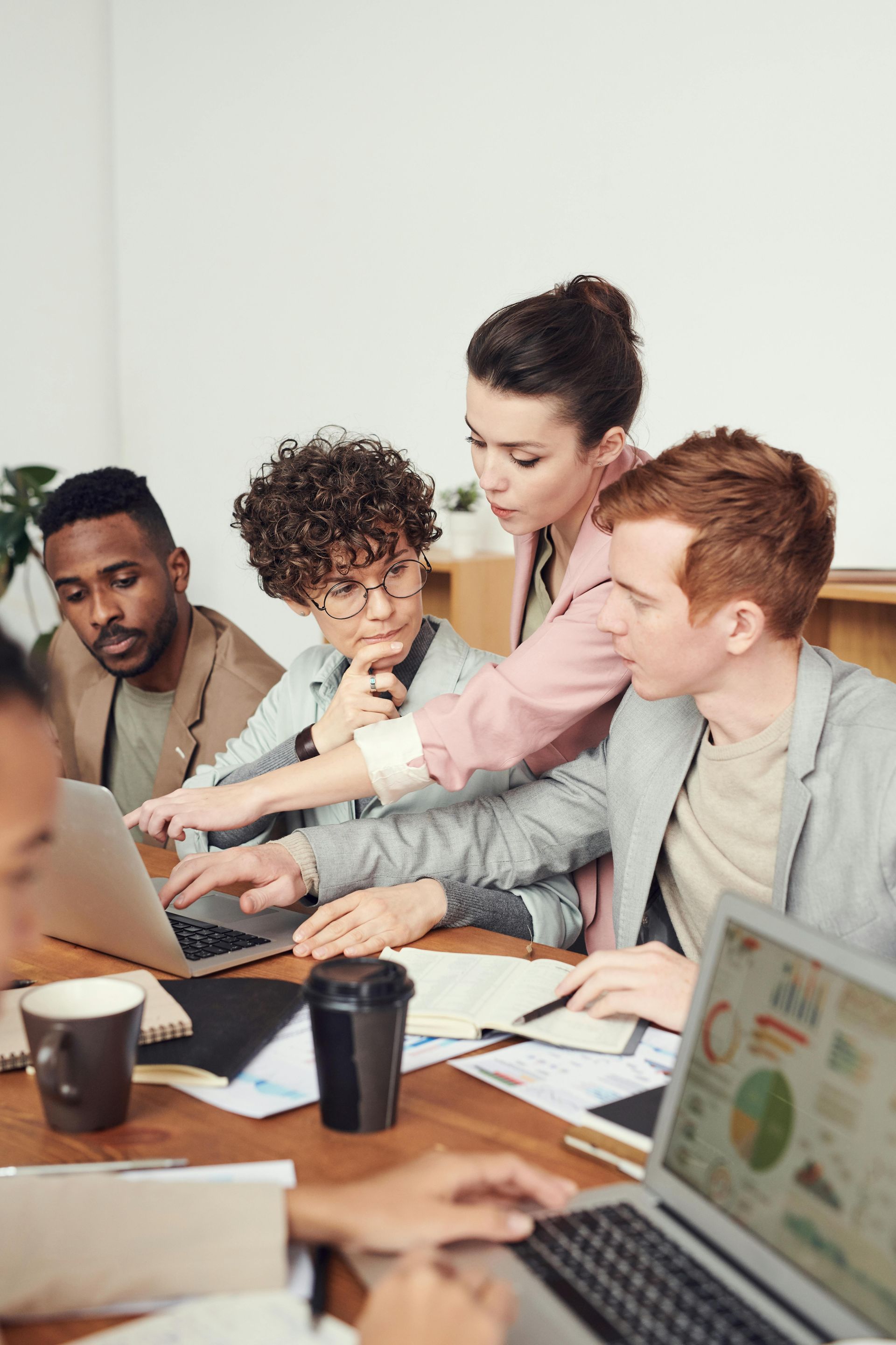 A group of people are sitting around a table looking at laptops.