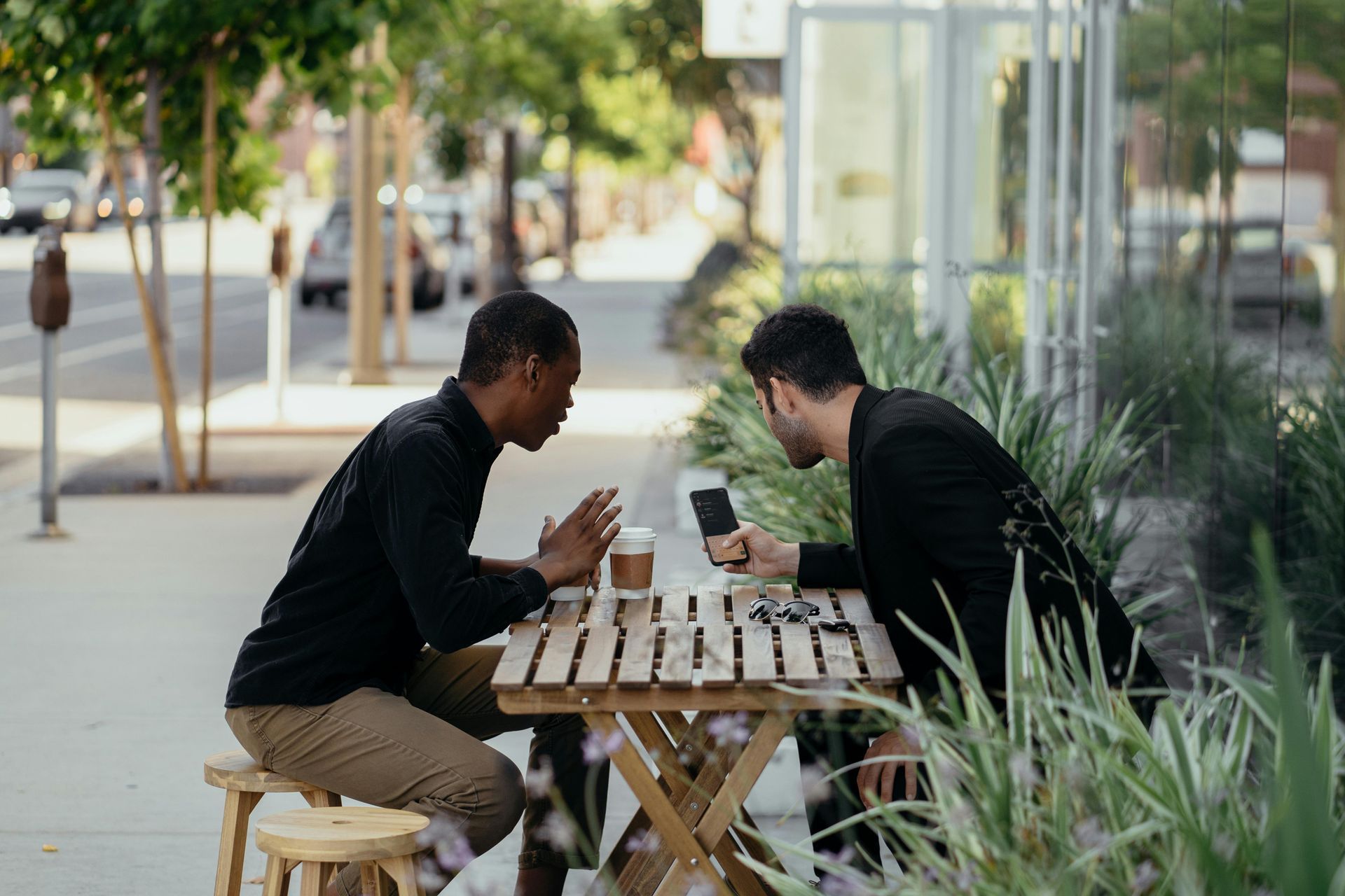 Two men are sitting at a table talking to each other.
