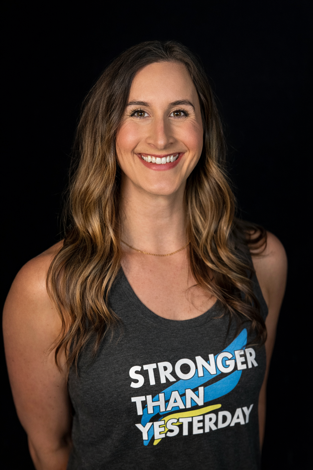 Smiling person in a dark tank top with “Stronger Than Yesterday” text on a black background