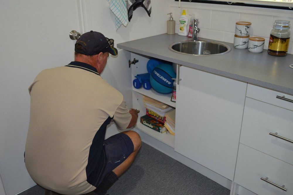 Pest Control Expert Inspecting Kitchen Cabinet