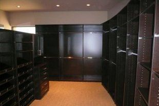 A large walk in closet with lots of shelves and drawers.