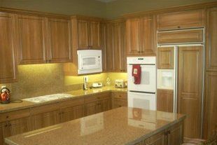 A kitchen with wooden cabinets , granite counter tops , stainless steel appliances and a large island.