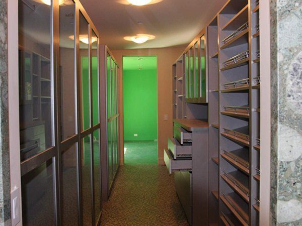 A hallway with lots of shelves and drawers and a green wall