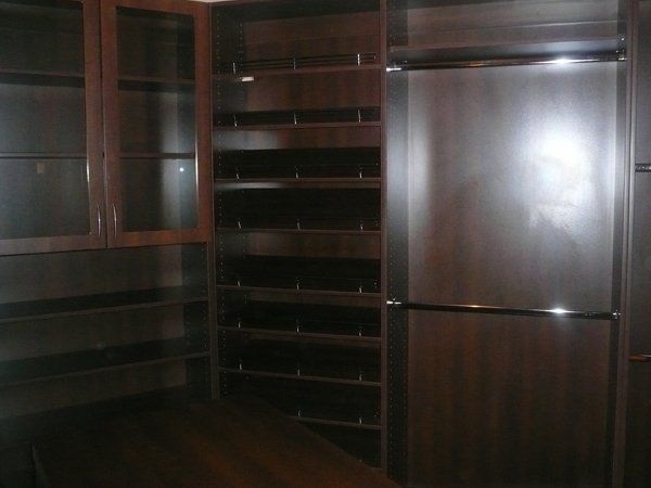 A dark room with lots of shelves and a stainless steel refrigerator