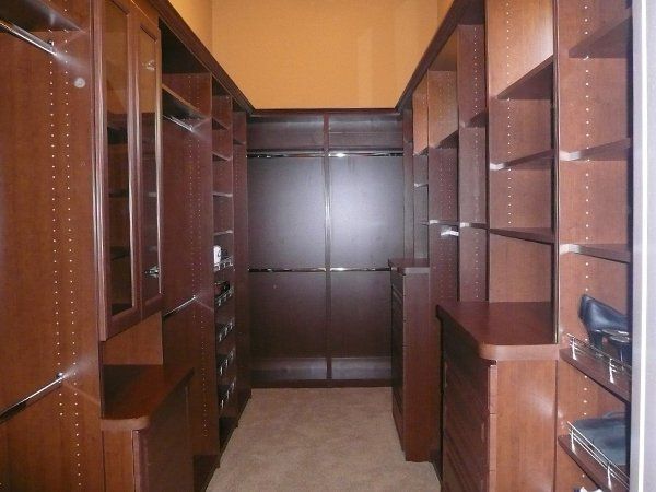 A walk in closet with lots of shelves and cabinets