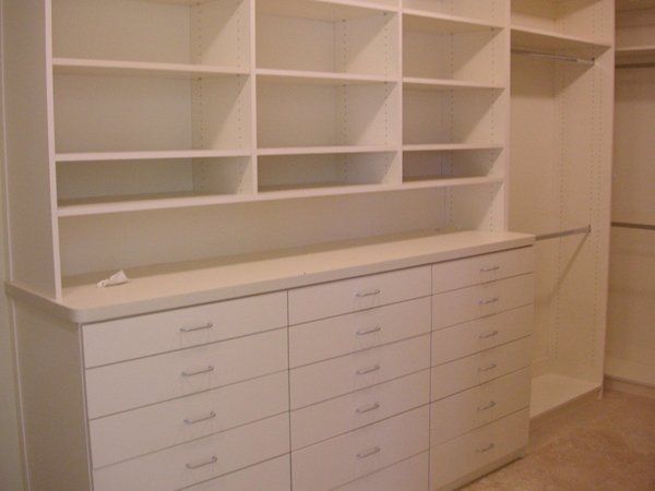 A walk in closet with lots of shelves and drawers