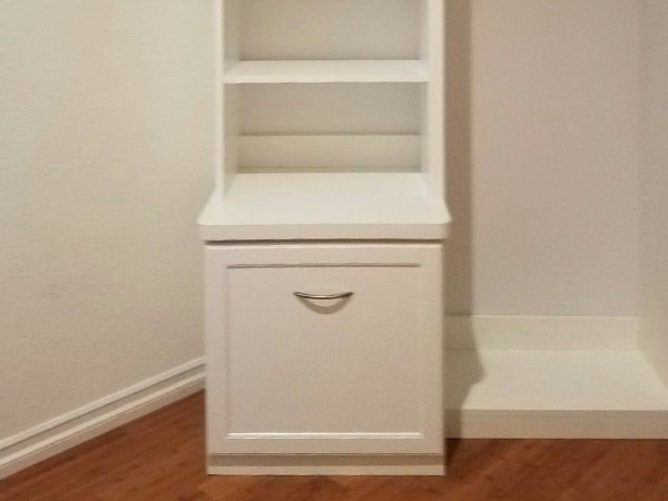 A white cabinet with a drawer and shelves in a room.