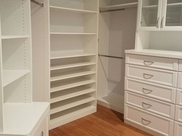 A walk in closet with lots of shelves and drawers