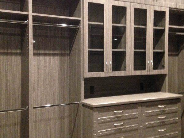 A walk in closet with glass doors and drawers