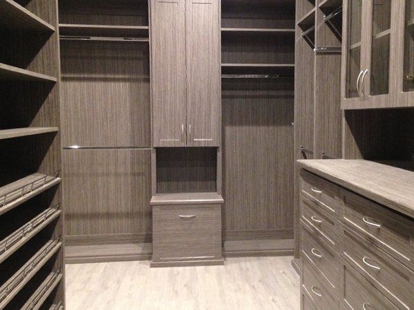 A walk in closet with lots of shelves and drawers