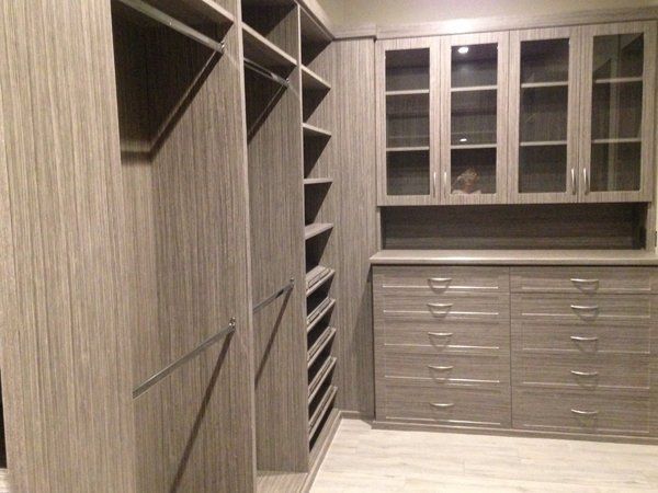 A walk in closet with lots of shelves and drawers and glass doors.