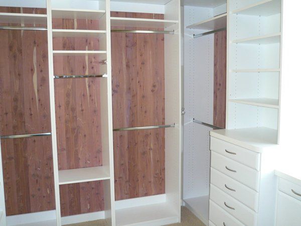 A walk in closet with wooden walls and white shelves