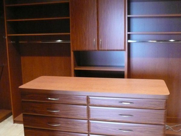 A large wooden dresser in a walk in closet