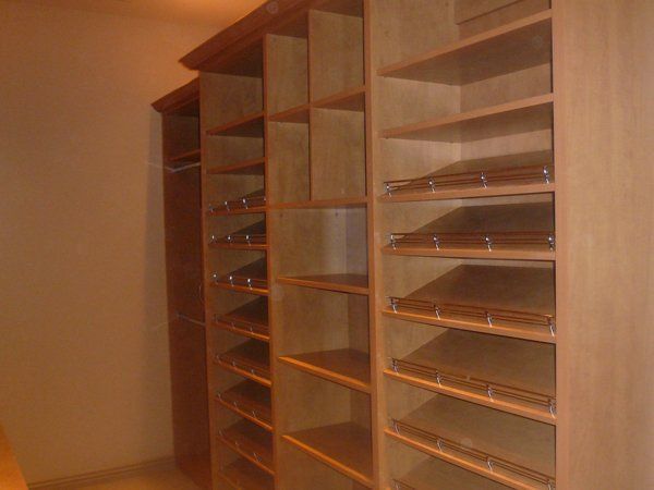 A closet with a lot of shelves and a few clothes on them