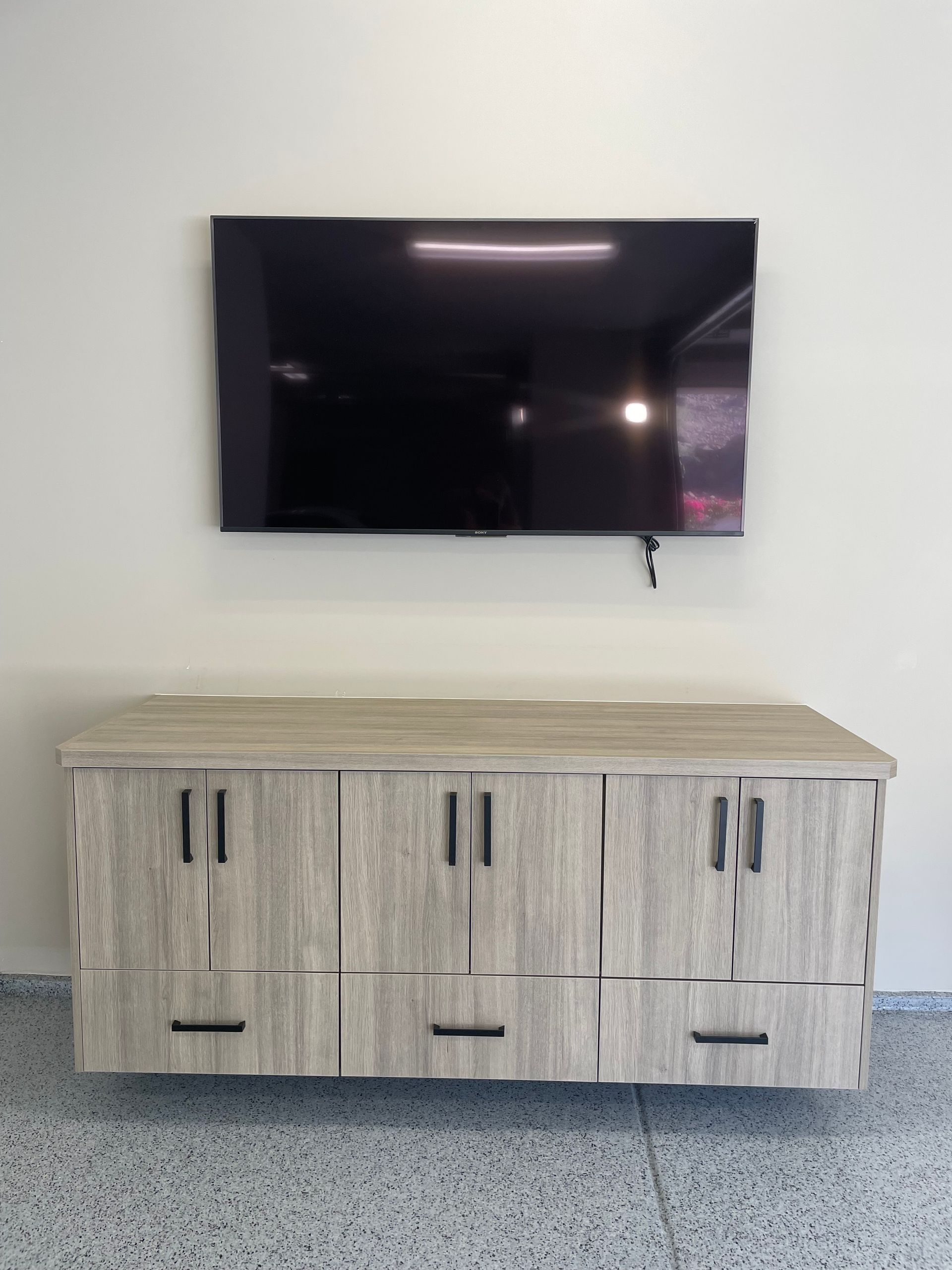 A flat screen tv mounted on a wall above a wooden cabinet