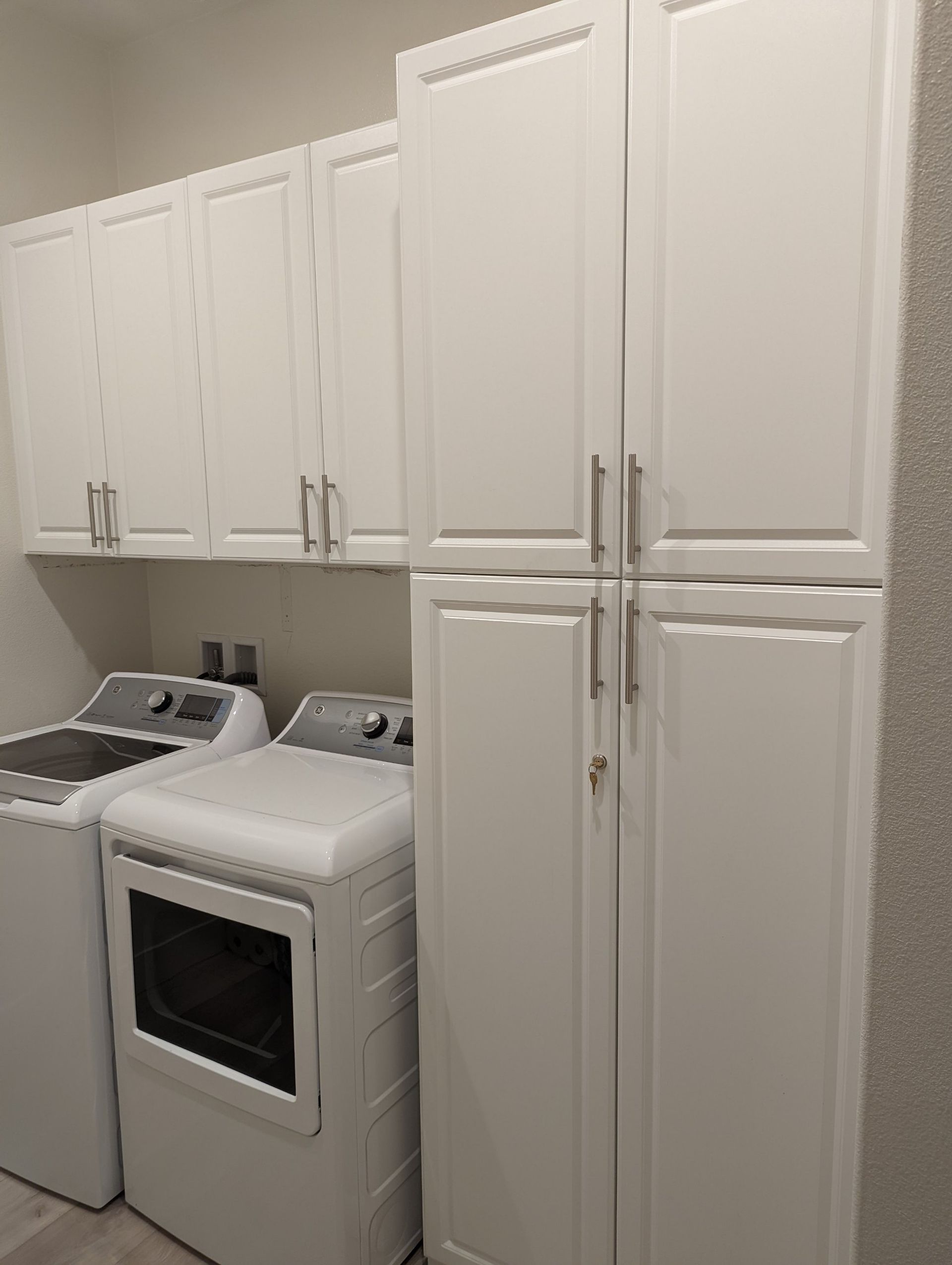 A laundry room with a washer and dryer and white cabinets.