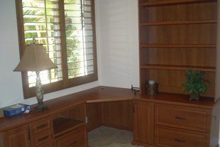 A room with a desk , bookshelf , lamp and window.