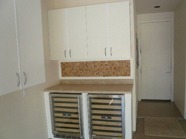 A kitchen with white cabinets and a wine cooler