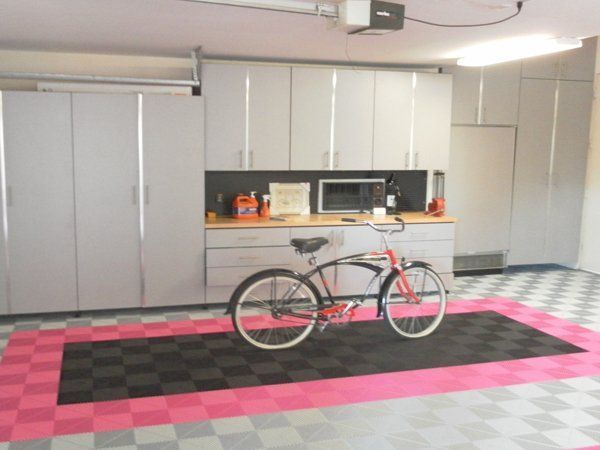 A bicycle is parked on a checkered floor in a garage