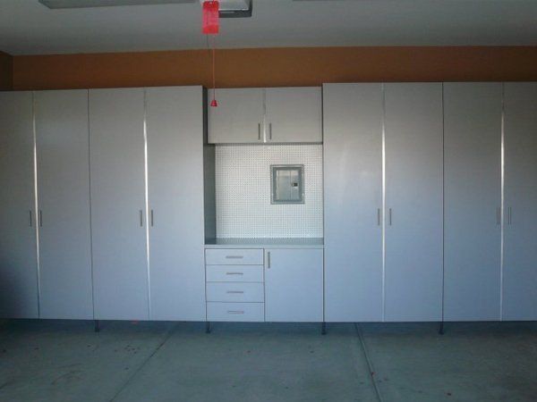 A garage with a lot of white cabinets and drawers